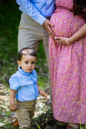 a toddler standing with his parents.