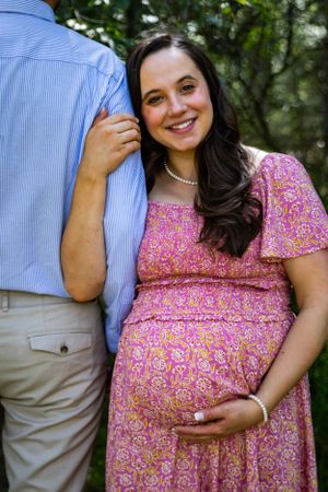 a pregnant woman holding her husbands arm and her baby bump.