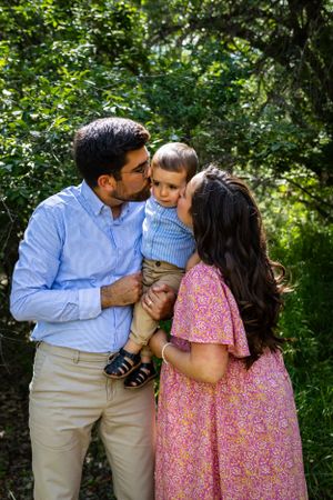 a couple kissing their son.