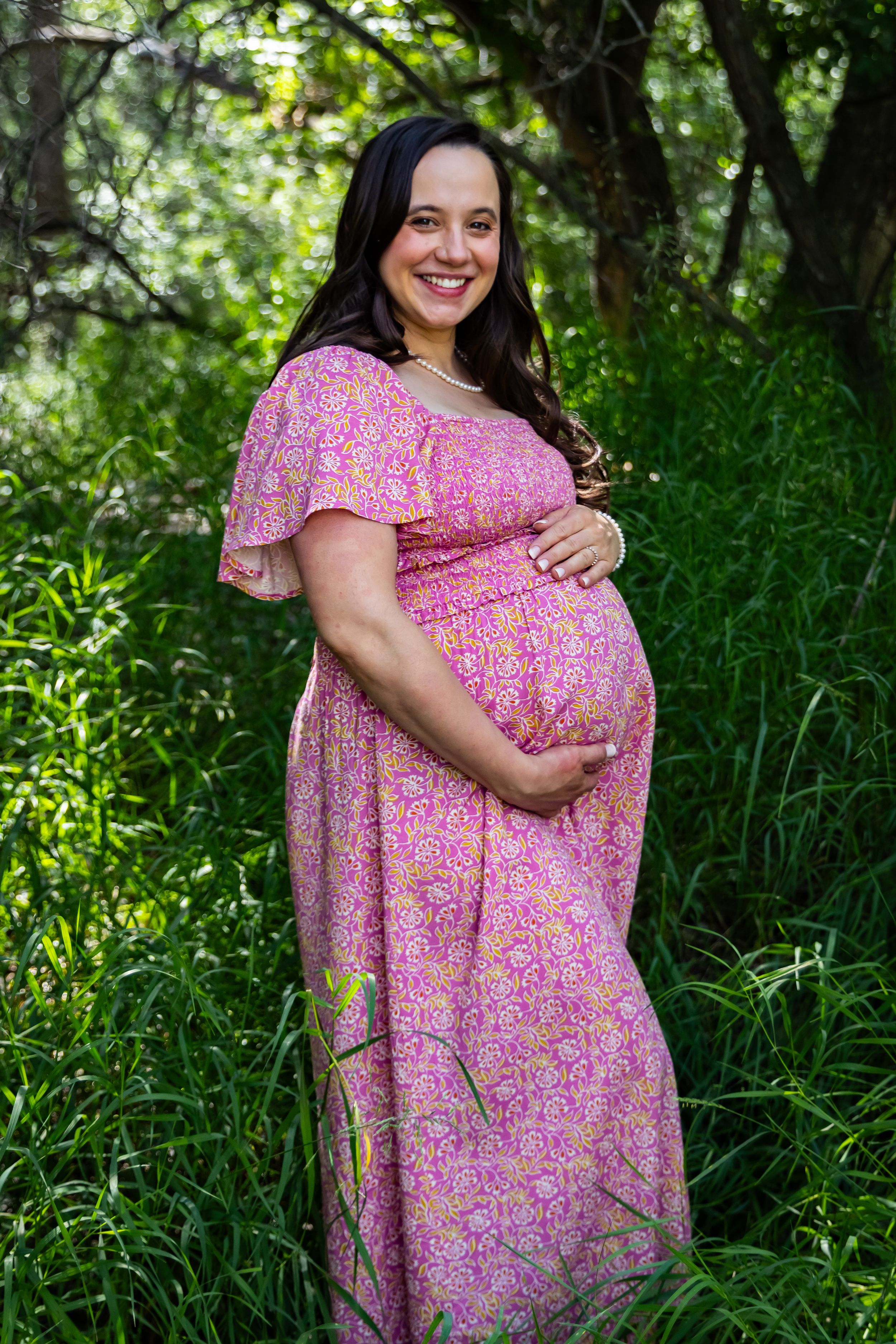 a pregnant woman standing in tall grass