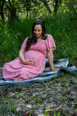 a pregnant woman sitting in tall grass