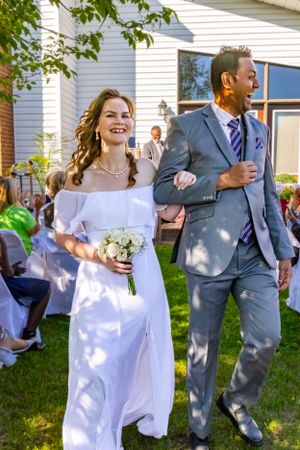 a bride and groom walk arm and arm grinning down the isle.
