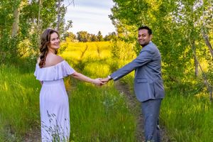 a couple holds hands in a field.
