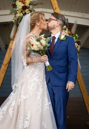 a bride and groom kissing in front of a wooden arch with flowers