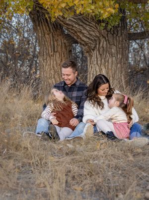 a family in front of a tree in autumn