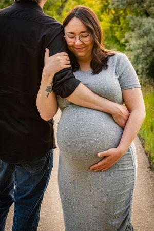 a pregnant woman holding her husbands arm and her baby bump.