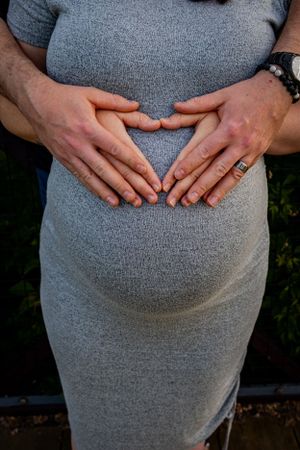hands on a baby bump shaping a heart.