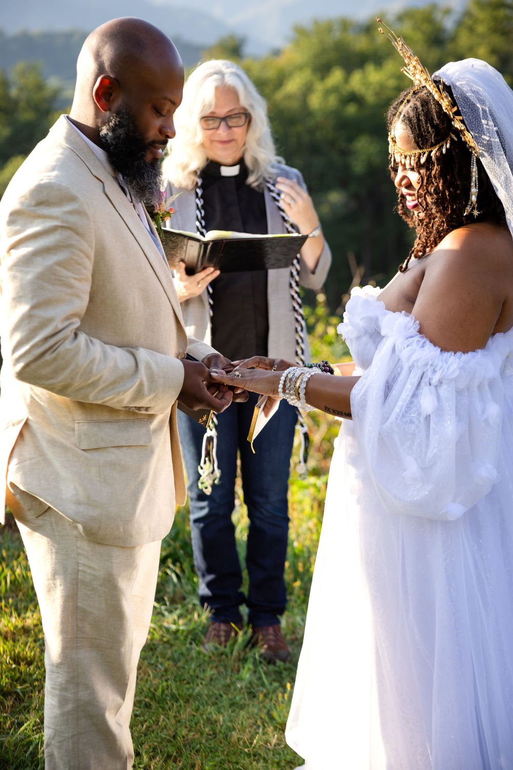Wedding ceremony in a scenic outdoor setting with couple exchanging rings.
