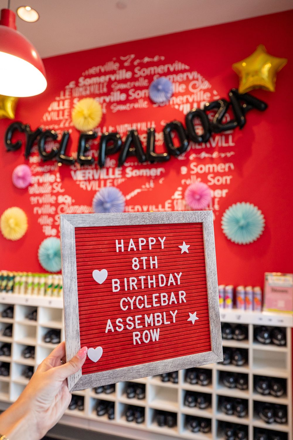 A letter board reads Happy 8th Birthday CycleBar Assembly Row at a Cyclepalooza celebration with colorful decorations.