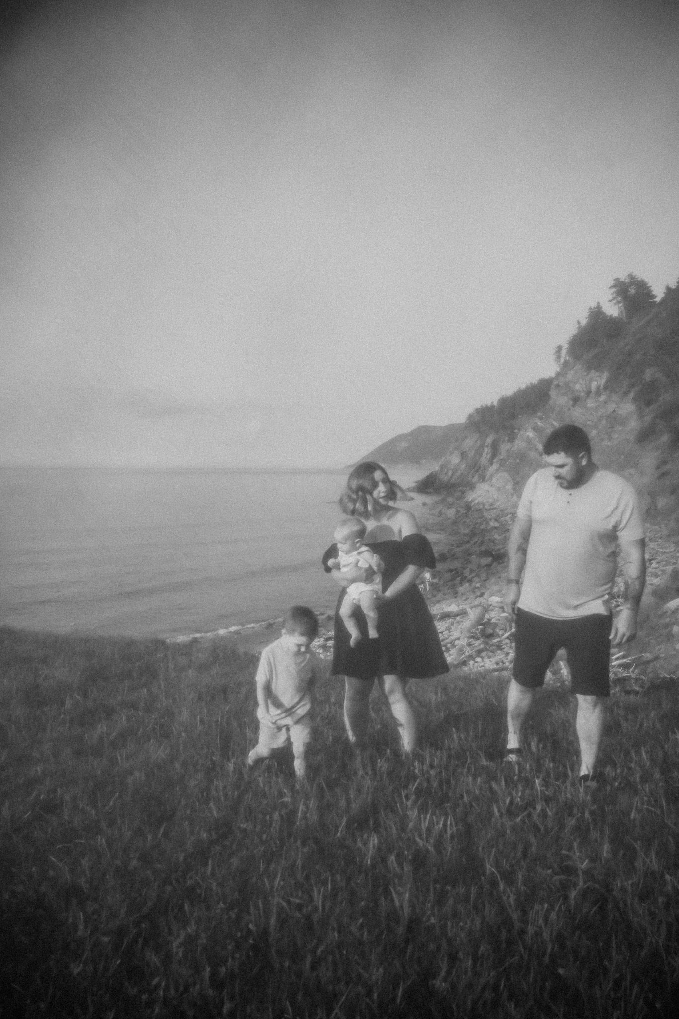 Vintage-style photograph of a family standing together on a grassy coastal cliff.