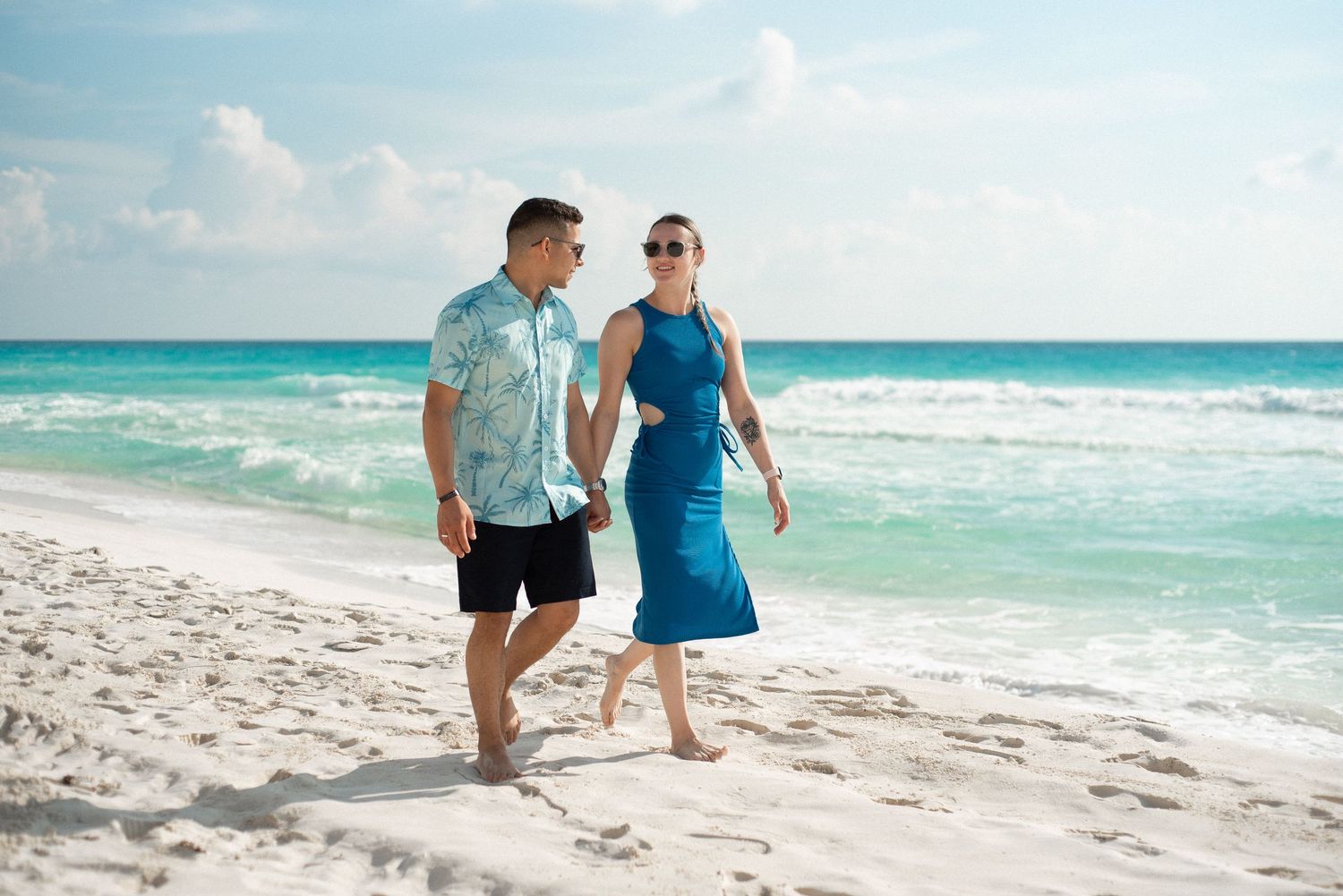 Jola and Bruno holding hands while walking by the beach of Cancun, Mexico during their engagement photoshoot