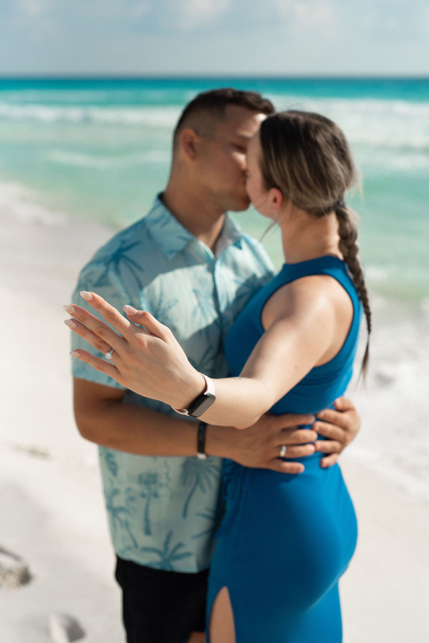 Portrait of a couple kissing while she shows her engagement ring to the camera during a photo session in Cancun