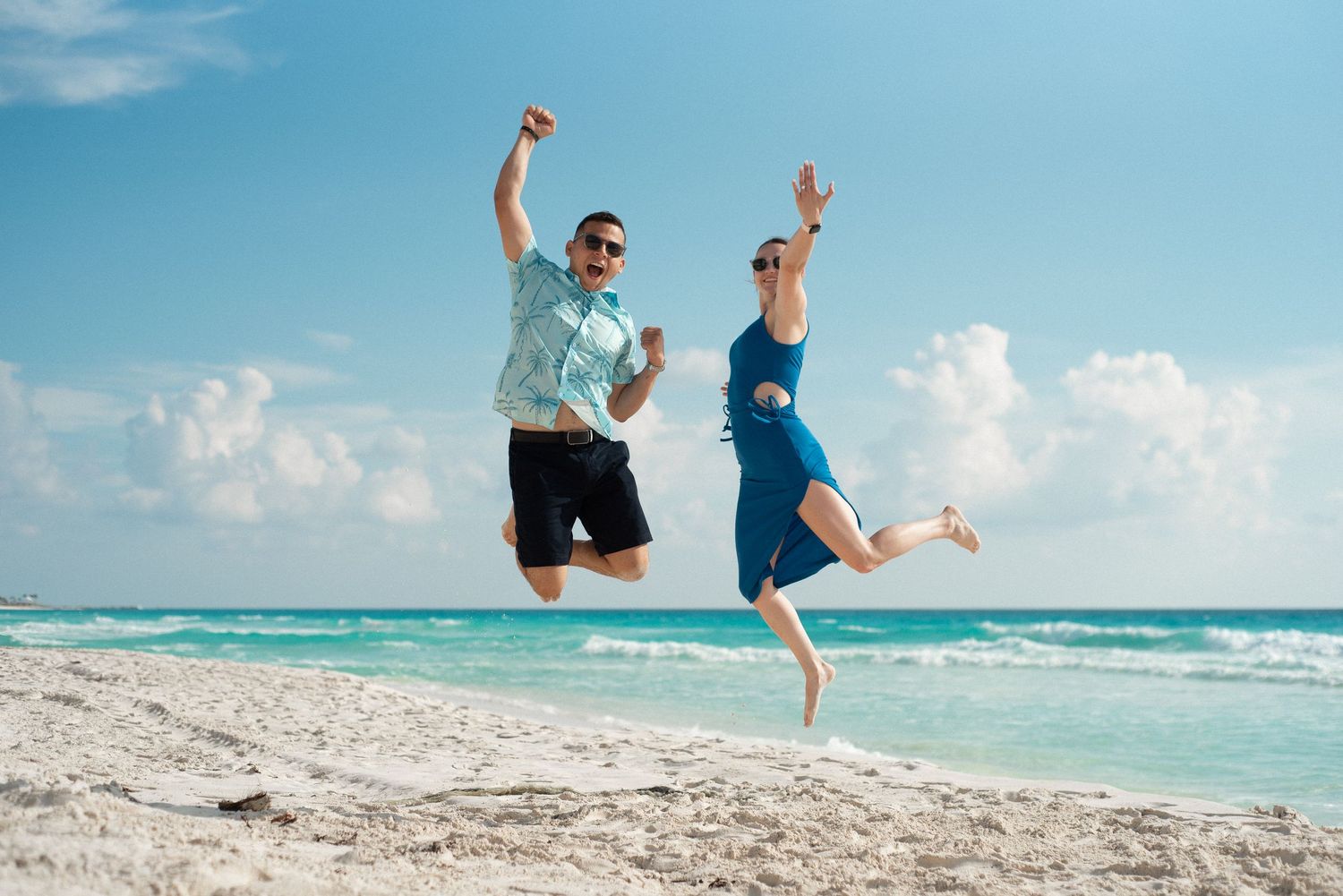 Jola & Bruno on the beach of Cancun, Mexico, jumping and celebrating their recent engagement on a photography session