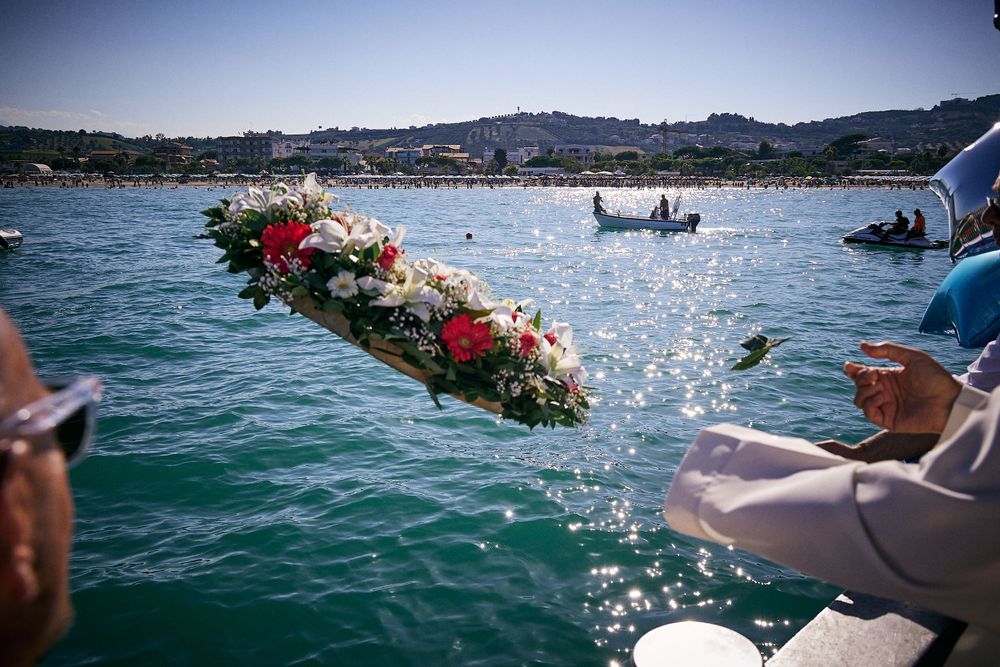 Colorful flower wreath being placed into sparkling blue ocean waters.