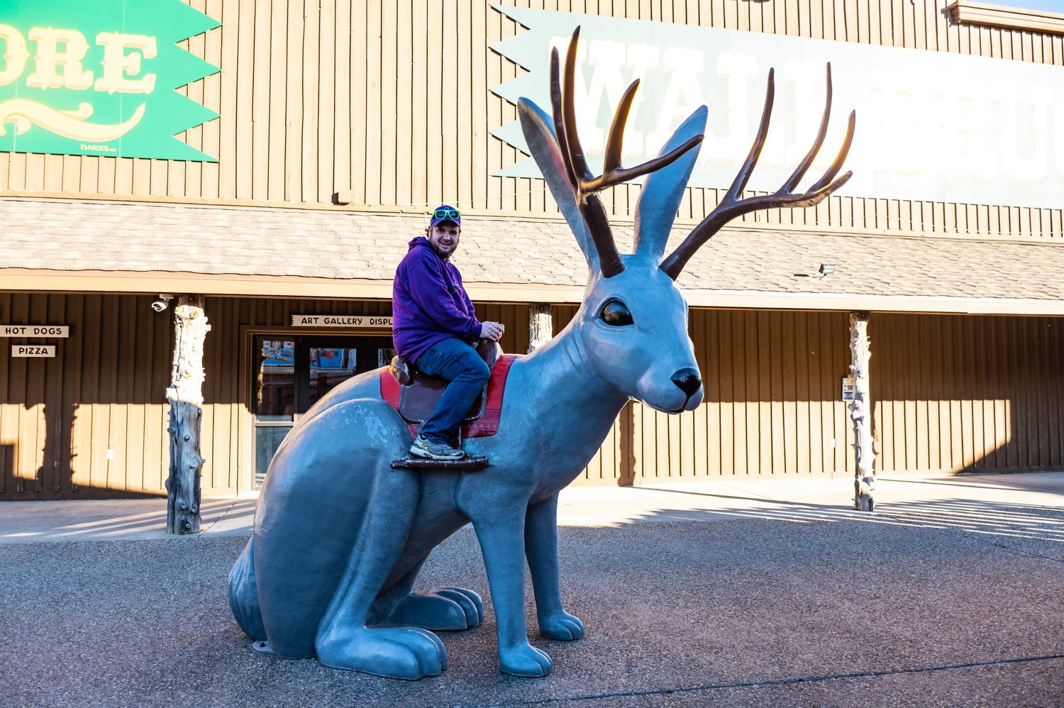 Large blue jackalope statue with antlers displayed outside a commercial building.