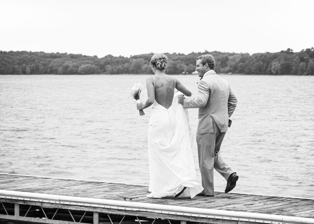 A couple on their wedding day shares a joyful moment while standing on a dock on Lake Champlain in Burlington, Vermont.