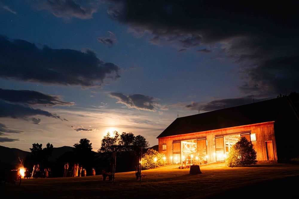 Illuminated farmhouse silhouetted against a dramatic sunset sky.