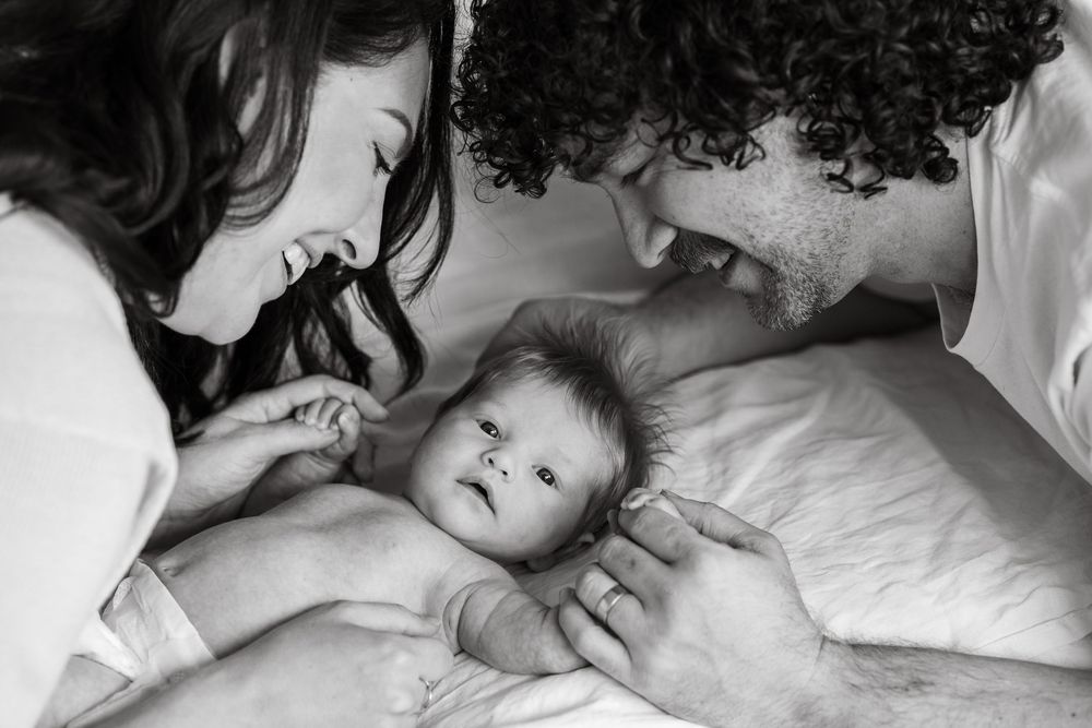 Adorable baby gazing directly at the camera while mom and dad lovingly look at their child, capturing a heartfelt family moment.
