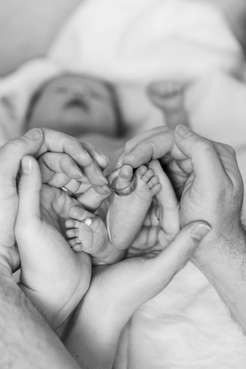 Close-up of a baby's tiny feet gently held by mom and dad's hands, forming a heart shape, capturing the love of family.