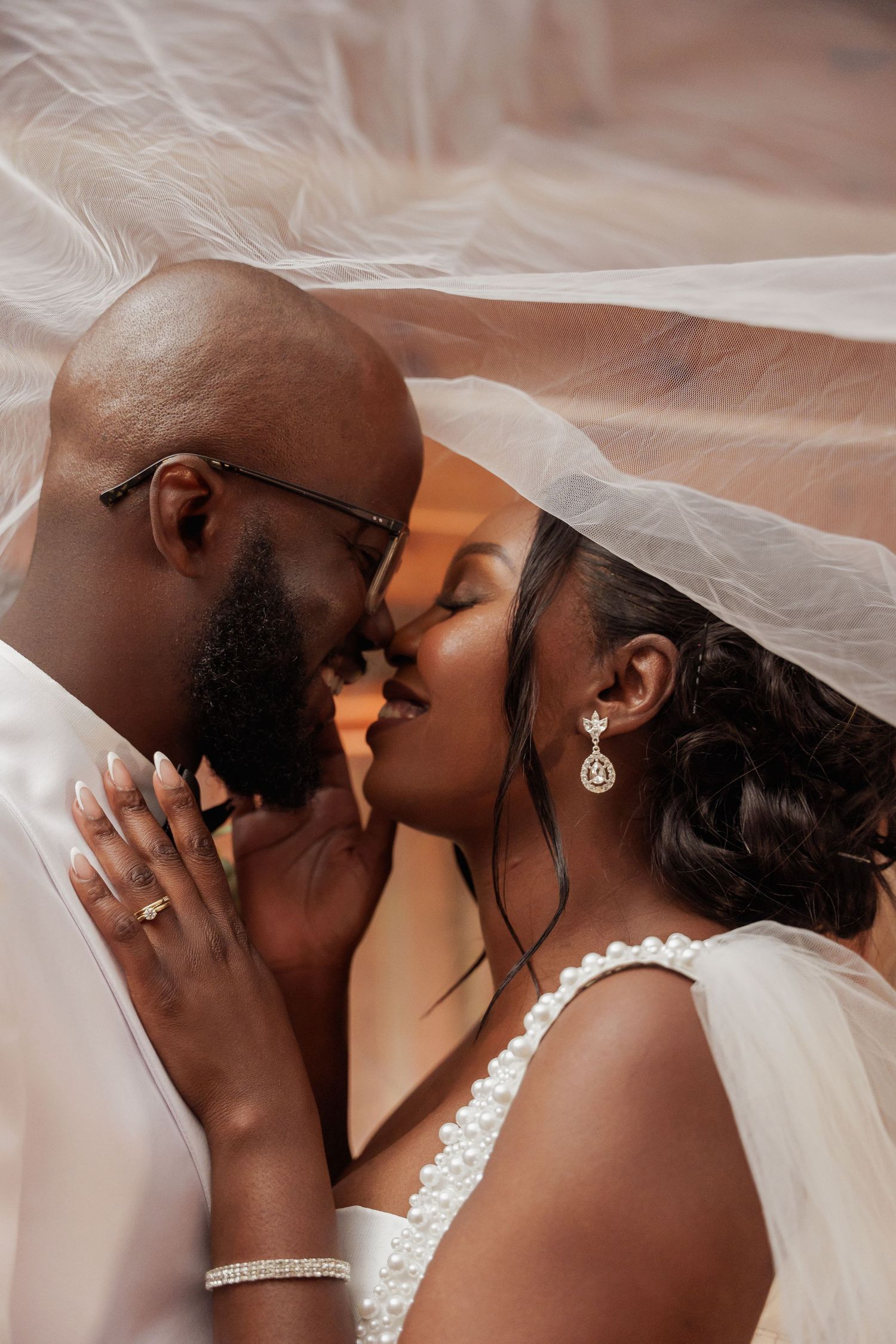 Intimate wedding portrait of couple sharing tender moment under bridal veil.