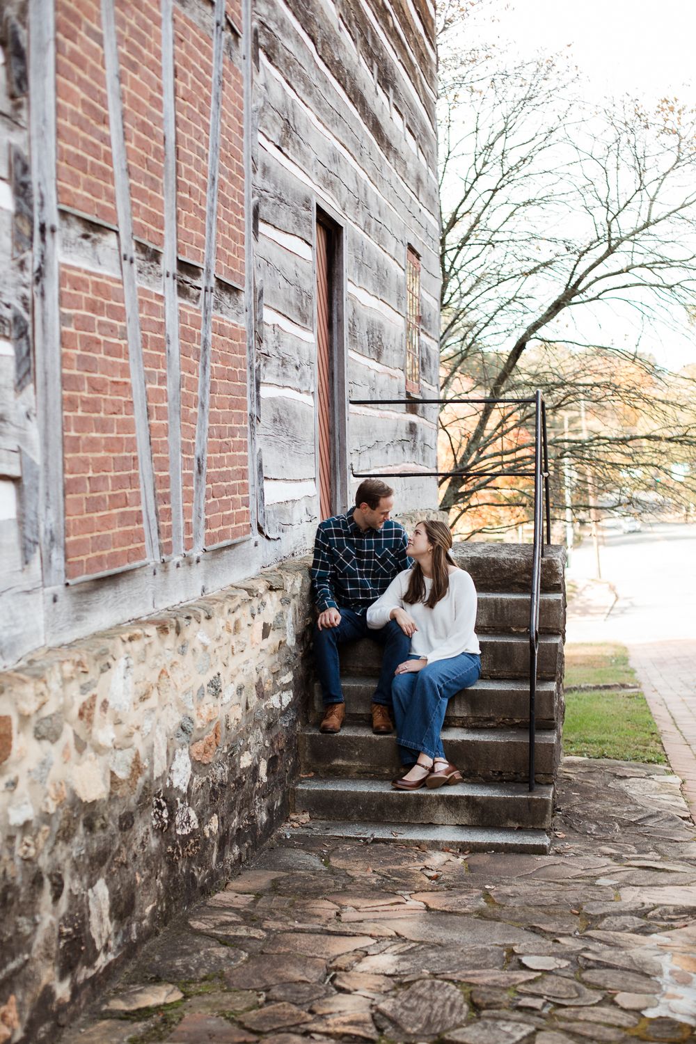 Couple sitting on stone steps of historic building during engagement photo session.