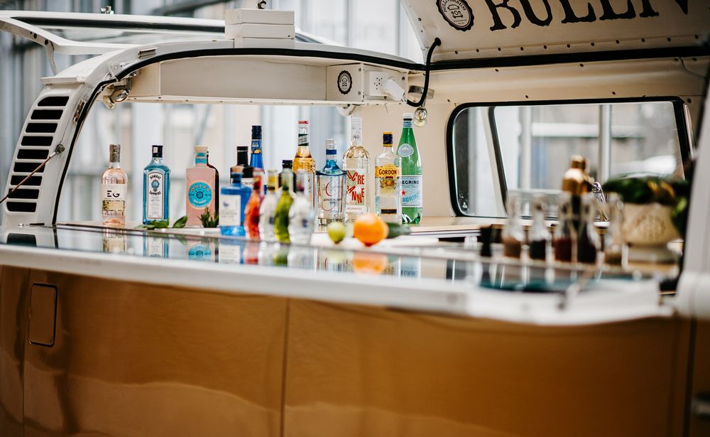 Vintage VW bus converted into a mobile cocktail bar with assorted liquor bottles on display.