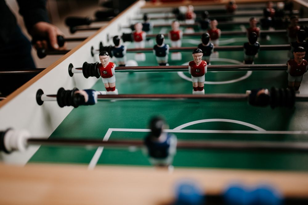 Close-up of colorful foosball table figures in red and blue on a green playing field.