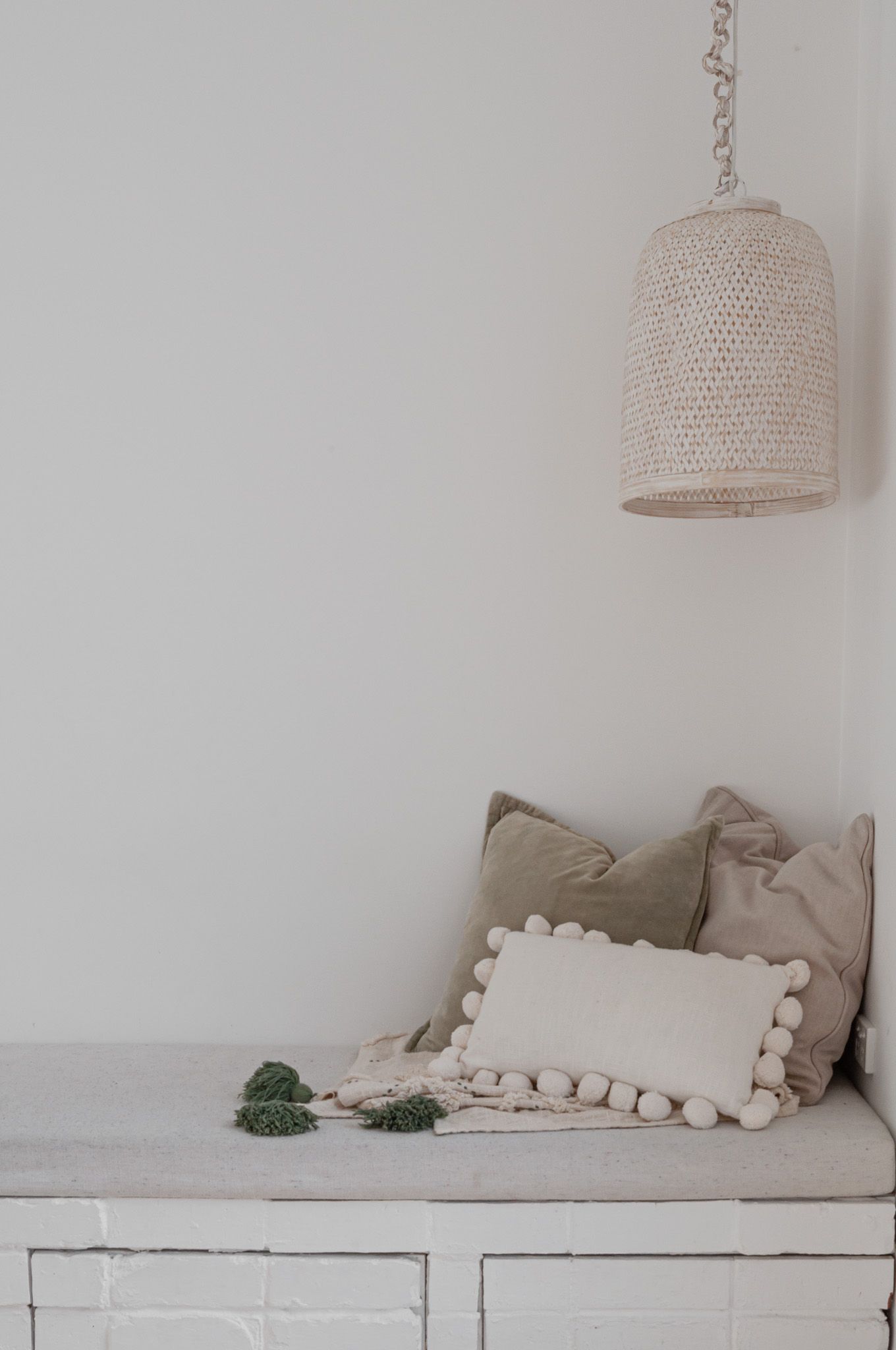 Cozy seating nook with textured pillows and woven pendant light in neutral tones.