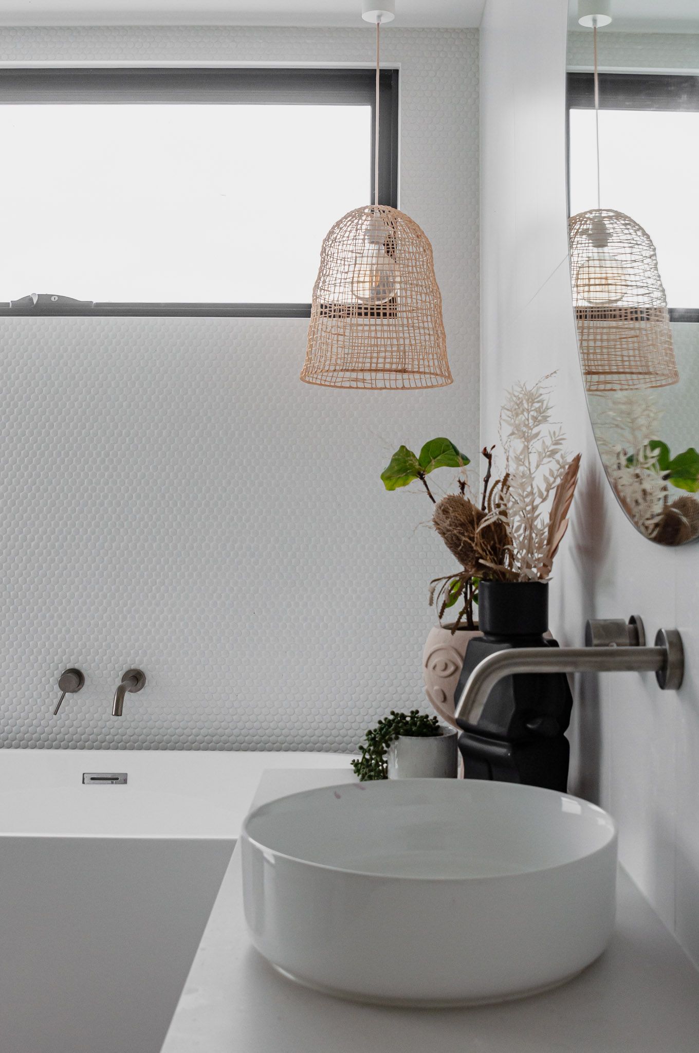 Contemporary bathroom with woven pendant lights, vessel sink, and floating shelf with plants.