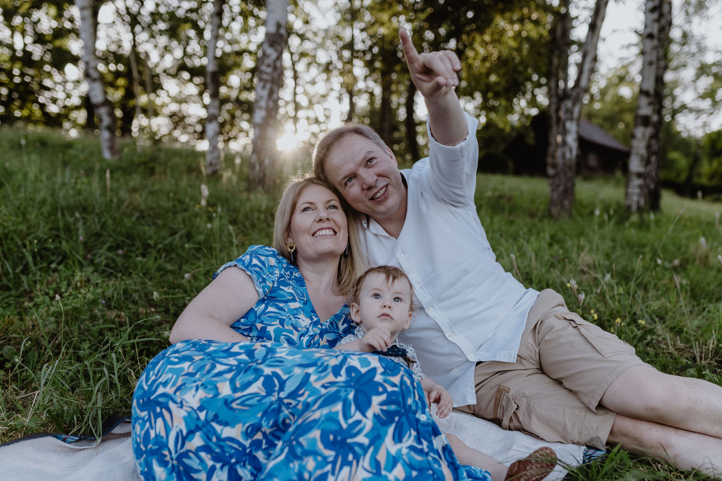 Heartwarming family portrait of three, smiling and relaxing on a blanket in the park.