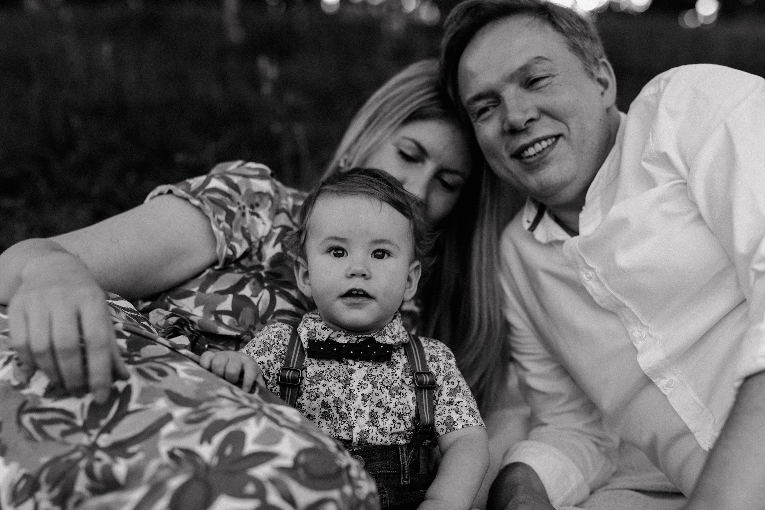 A joyful family moment with three members smiling on a picnic blanket in Jelenovac during a family photoshoot.