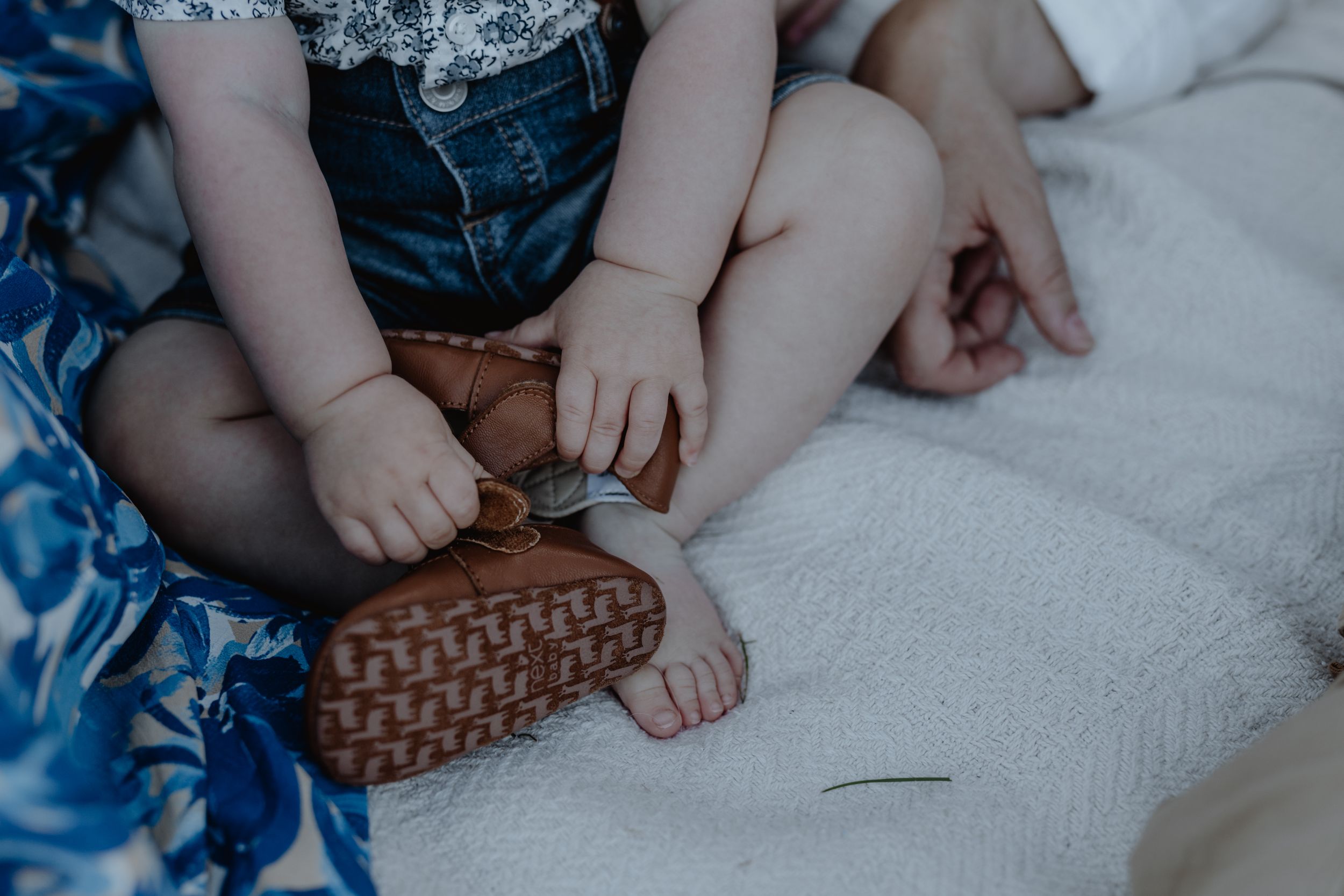 Detail shot of tiny baby feet and legs on a soft blanket, capturing a precious moment.