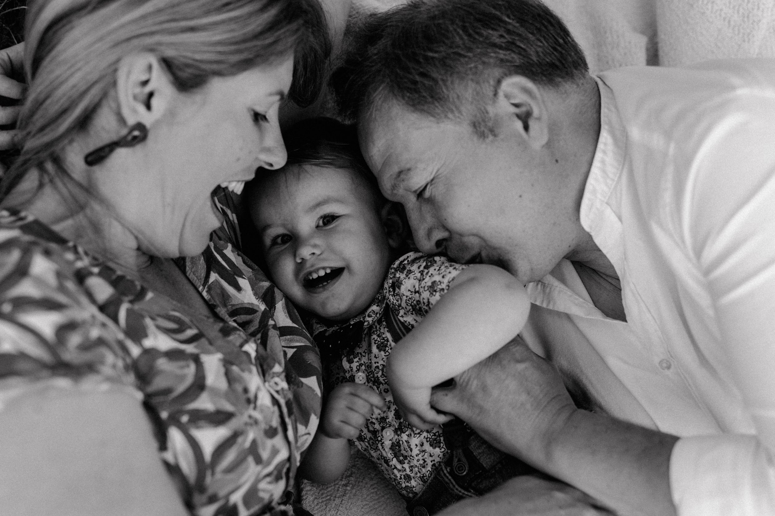 Black and white intimate family photo capturing joyful laughter and connection.