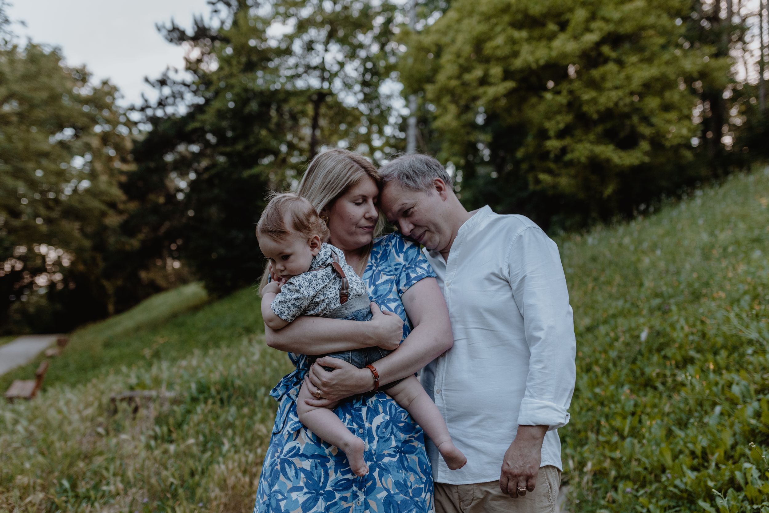 Family walking through the park, holding hands and sharing smiles during a relaxed photoshoot.