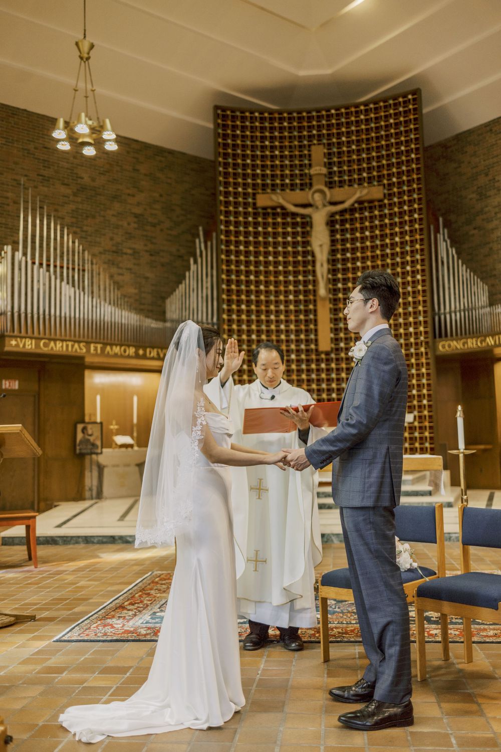 A couple sharing a special moment during their wedding ceremony in a modern church with brick walls and white accents.
