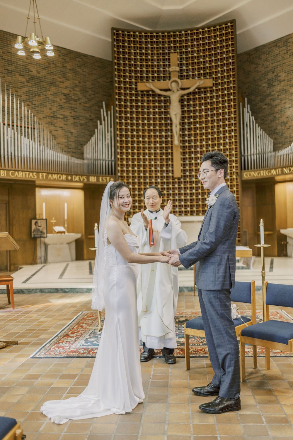 A traditional Catholic wedding ceremony taking place in a church with brick walls and a decorative wooden cross.