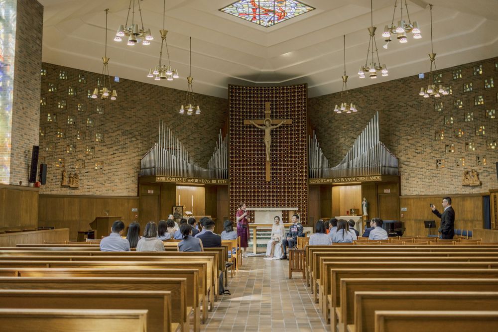 Spacious modern church interior with wooden pews and contemporary lighting fixtures.