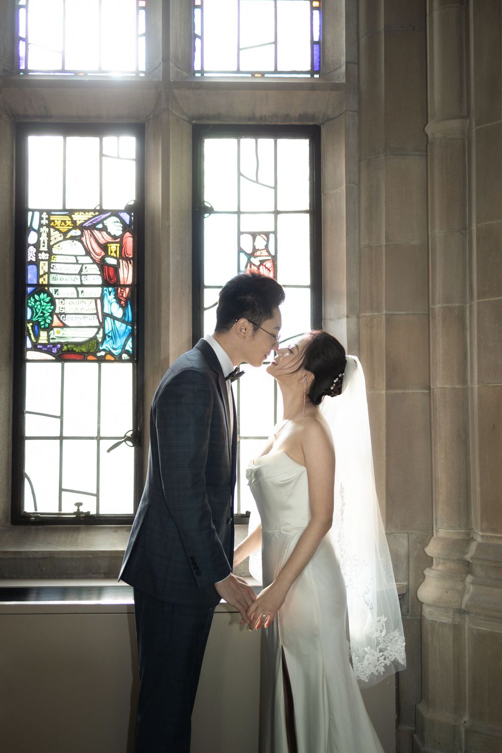 A romantic moment captured by window light in a Gothic style building interior.