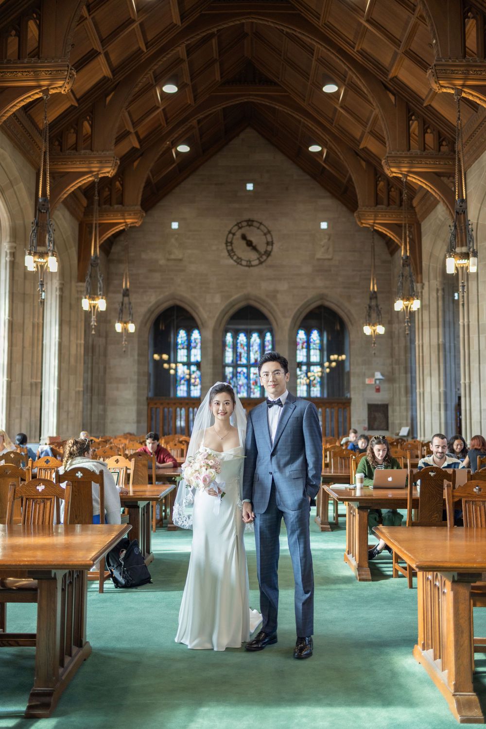 Gothic-style library hall with vaulted wooden ceiling, chandeliers, and green carpet.