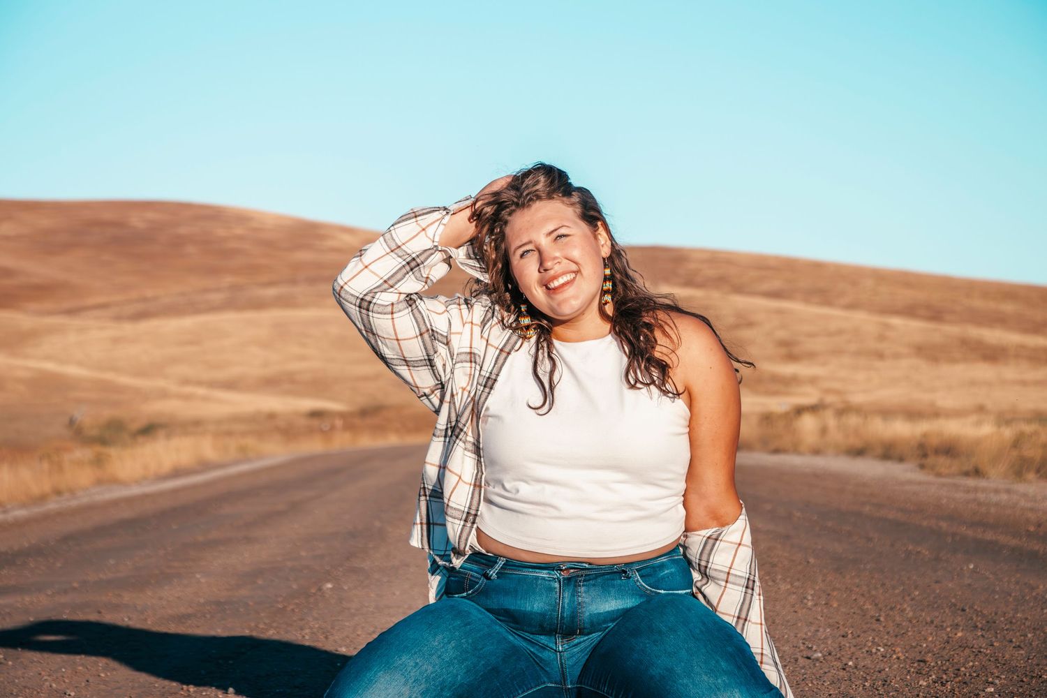 A casual outdoor portrait on a winding dirt road with rolling hills in the background on a sunny day.