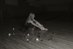 Person practicing yoga poses on a dark wooden floor at night.