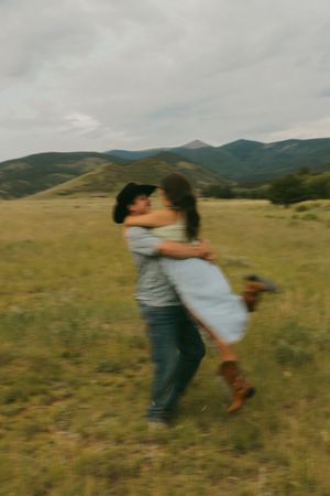 Playful spinning dance moment captured against rolling mountain landscape.