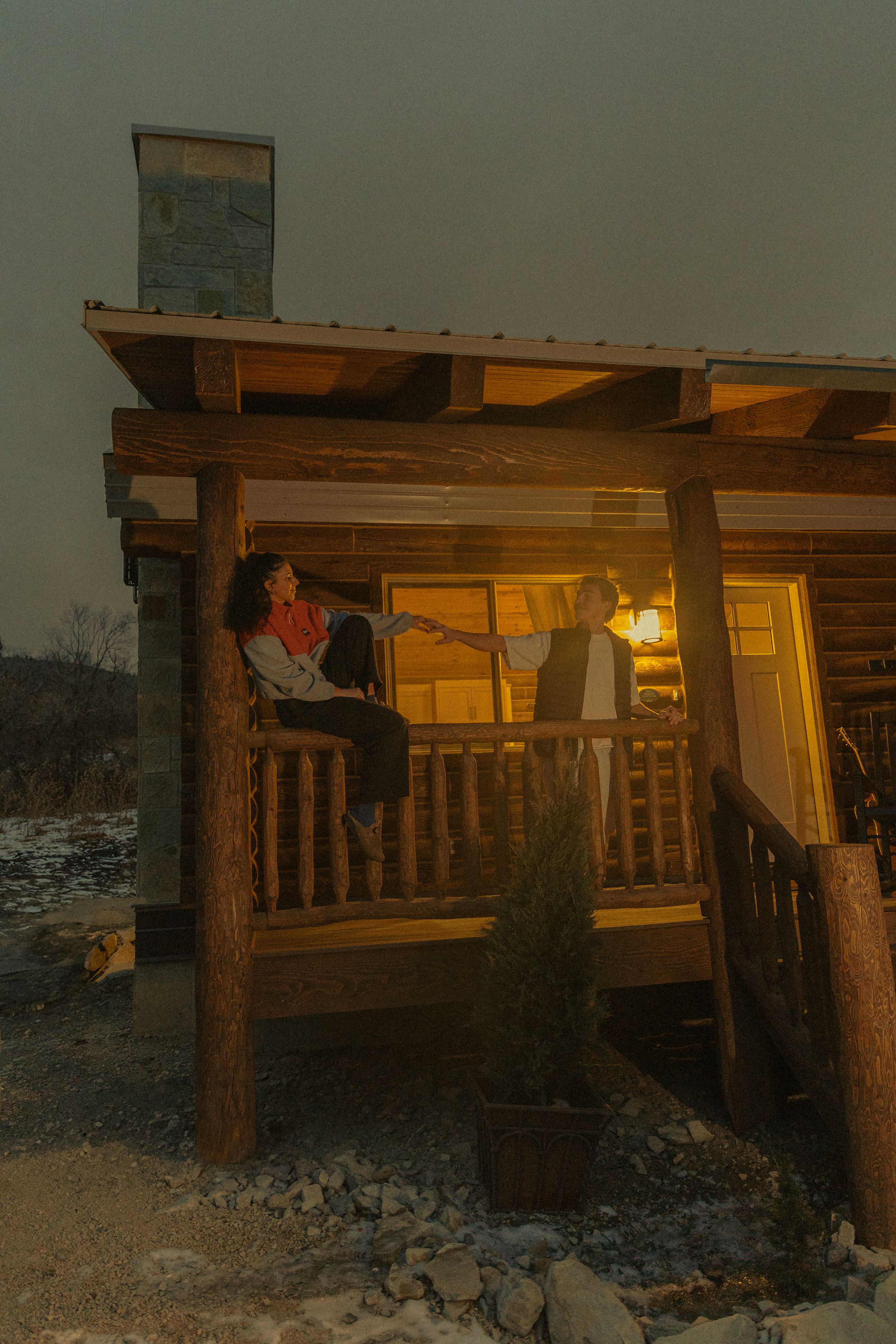 A rustic wooden cabin glows warmly at twilight with illuminated windows.