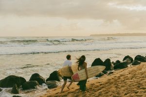 People sitting on a beach at sunset watching the waves roll in.