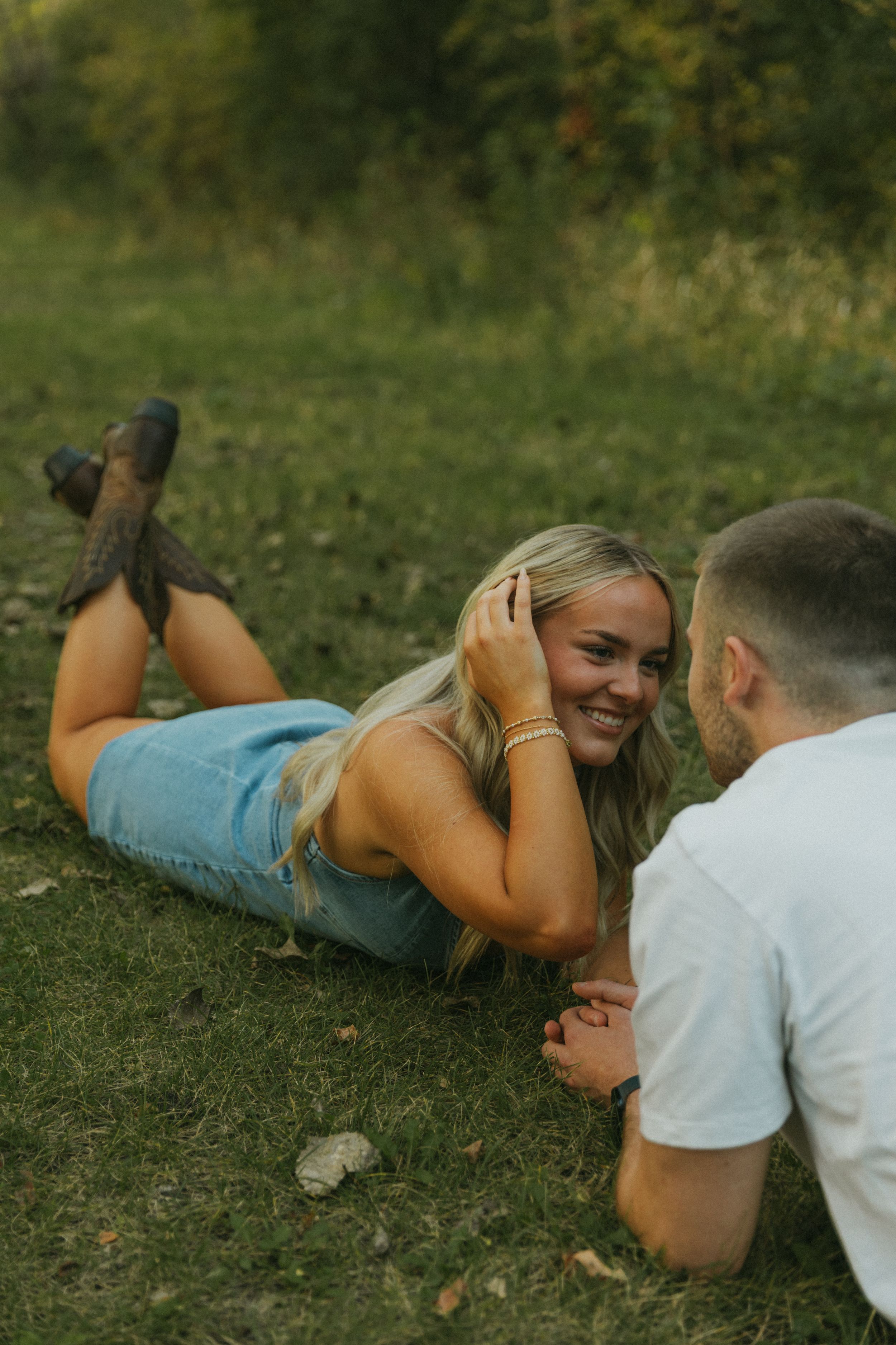 Couple laying in grass sharing a playful moment together outdoors.