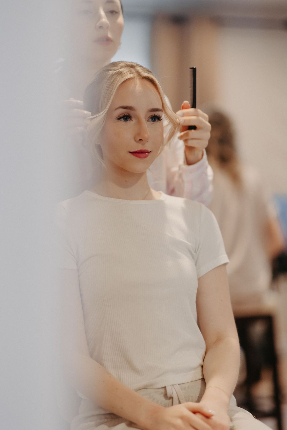 Bride getting ready in a white top during wedding preparations.
