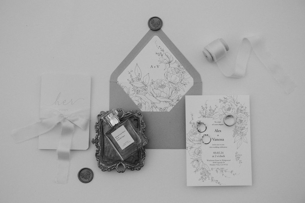 Black and white wedding stationery flat lay with floral designs and vintage-style decorative elements.