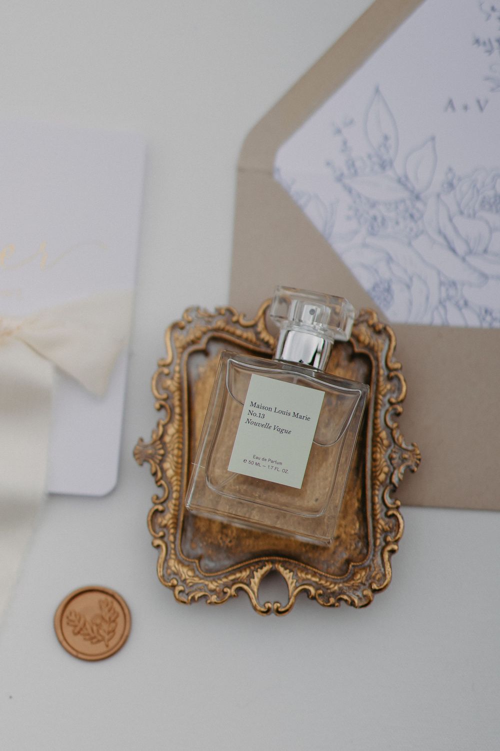 Perfume bottle displayed on ornate gold tray with wedding stationery details.