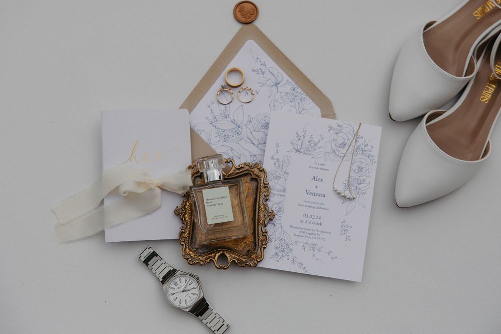 Wedding accessories flat lay featuring invitation, vintage frame, watch and bridal shoes.