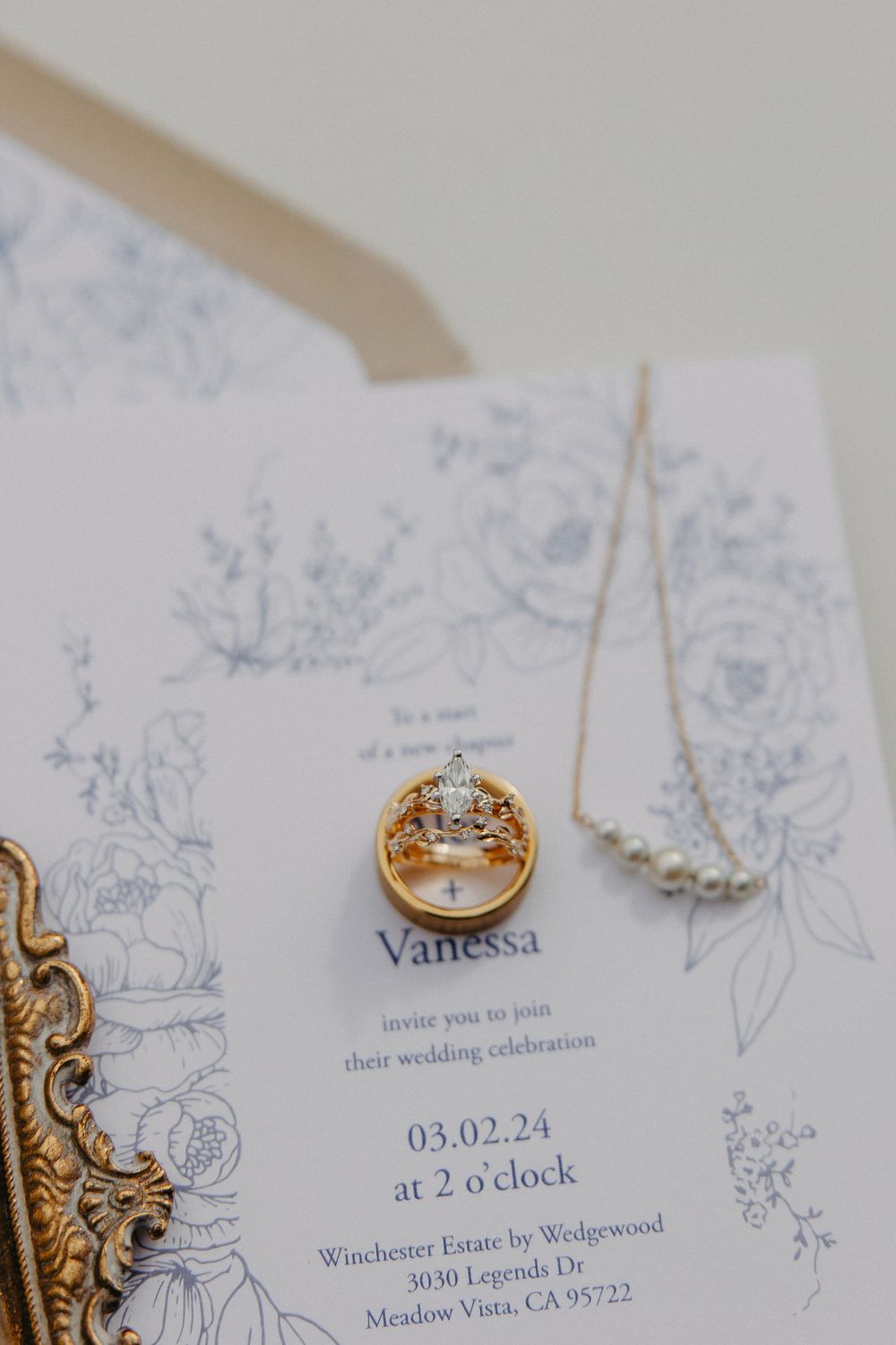 Wedding rings photographed on an elegant floral invitation with the date 03.02.24.